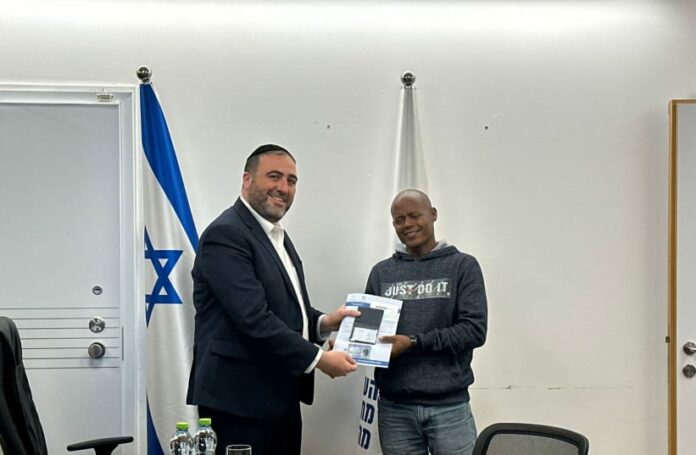 Minister of the Interior Moshe Arbel with Eritrean citizen Molugata Tsagai, who saved the life of an IDF officer on October 7. As a token of gratitude, Arbel had the Ministry grant residency status to Tsagai. November 26, 2023. (photo credit: COURTESY INTERIOR MINISTRY)